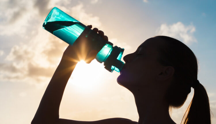 ورزشکار با تصویر تیره در حال نوشیدن از بطری آب