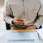 کار مرد با موبایل جلوی لپتاپ