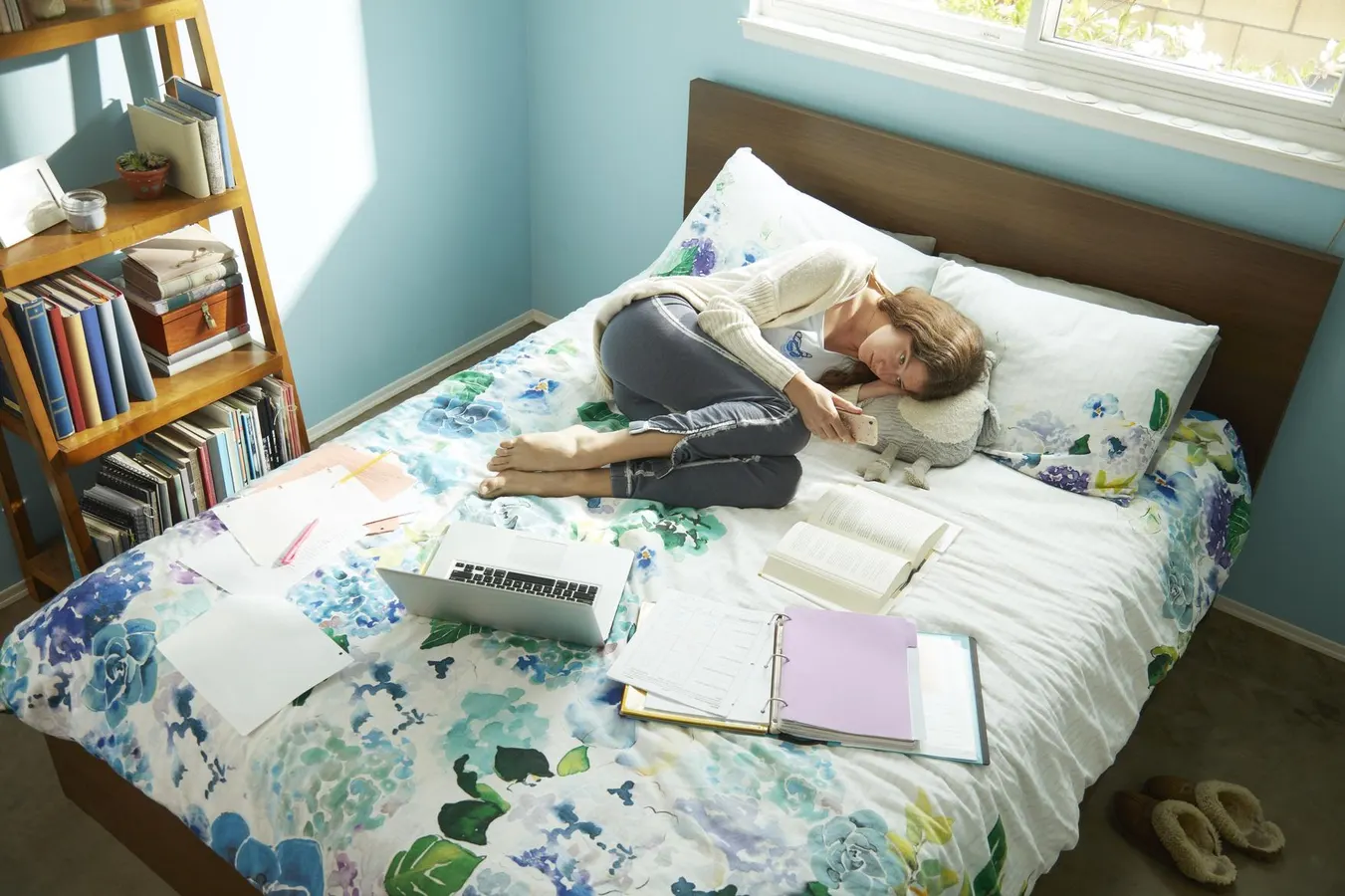 دراز کشیدن دختر در تختخواب با کتاب ها